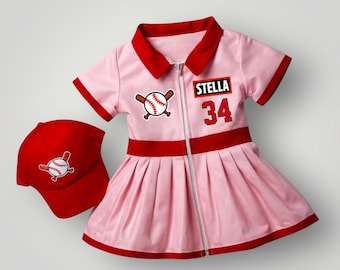 May include: A light pink short-sleeve dress with a red collar, red waistband, and red hem. The dress features a front zipper, a baseball graphic, and a black rectangular patch with the white text STELLA above the red number 34. A red baseball cap.