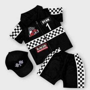 May include: A black short-sleeved collared shirt with a zipper, featuring a checkered pattern on the sleeves and chest, the name RYAN, the number 1, a red race car graphic, and the word RACER. Includes matching black shorts and a black baseball cap.