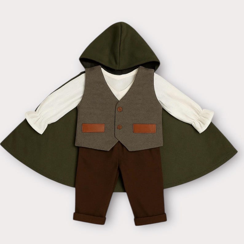May include: A set consisting of a dark olive green hooded cloak, a cream-colored long-sleeve shirt with ruffled cuffs, a grey vest with two brown rectangular pockets and two buttons, and solid dark brown trousers with cuffed hems.