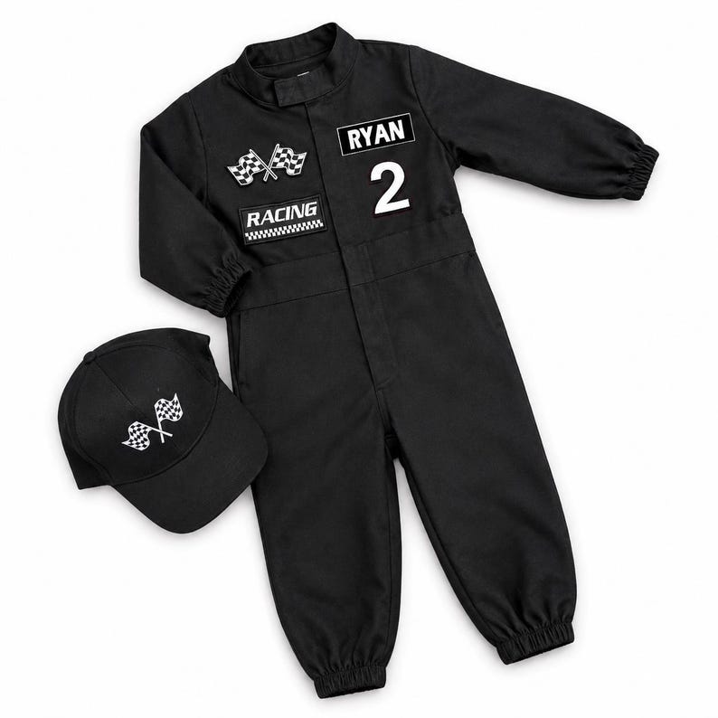 Op de afbeelding: Een zwarte jumpsuit met lange mouwen, elastische boorden en een bijpassende baseballpet. De jumpsuit heeft een witte patch met gekruiste geblokte vlaggen, een RACING-patch, de naam RYAN en het cijfer 2. De pet heeft een geblokt vlag-embleem.