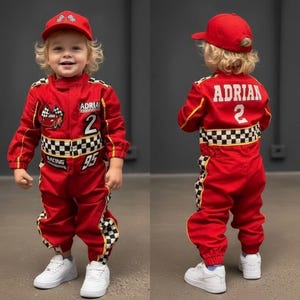 Puede incluir: Un mono de carreras rojo y una gorra a juego con un patrón de cuadros blancos y negros, el nombre ADRIAN, el número 2 y un gráfico de un coche rojo con banderas de cuadros. El mono incluye zapatillas blancas y mangas largas con puños.