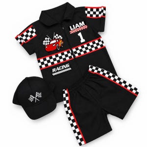 Puede incluir: Un conjunto de camisa negra de manga corta con cremallera, pantalones cortos y gorra de béisbol. La camisa muestra un coche de carreras rojo, el nombre LIAM, el número 1 y la palabra RACING. Todas las piezas tienen cuadros blancos y negros.