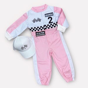 Op de afbeelding: Een roze en wit racepak met de naam "Georgia" en het nummer "2" op de borst. Het pak heeft een dambordpatroon en het woord "RACING". Een bijpassende witte hoed met geblokte vlaggen is inbegrepen.