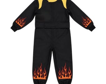 May include: A black long-sleeve jumpsuit featuring a yellow collar and shoulder accents. The garment includes orange and red flame graphics on the lower sleeves and lower pant legs, a central front zipper closure, and a waist belt with a hook-and-loop fastener.