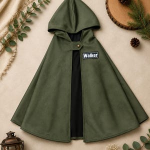 Puede incluir: Una capa con capucha de color verde oliva con forro interior negro. La prenda cuenta con un cierre de bot&oacute;n de color lat&oacute;n en el cuello y un parche rectangular negro en el pecho con el texto blanco Walker impreso en una fuente sans-serif.