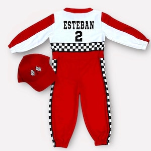 May include: A red and white racing-style jumpsuit featuring long sleeves, a black and white checkered band across the waist, and vertical checkered side stripes. The chest displays the name ESTEBAN and the number 2. A matching red cap has checkered flags.