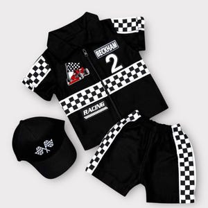 May include: A black short-sleeve collared shirt with a zipper, featuring a checkered pattern on the sleeves and midsection, a red race car graphic, the text "BECKHAM 2" and "RACING", matching black shorts with checkered side stripes, and a black cap.