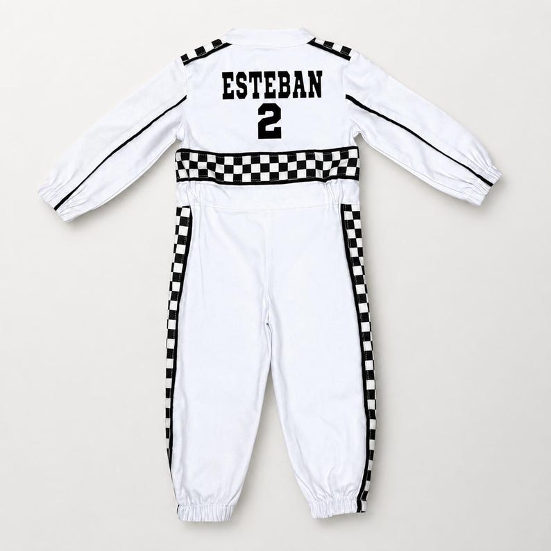 May include: A white long-sleeve jumpsuit featuring black and white checkered patterns along the waist and down the sides of the legs. The back displays the name ESTEBAN in black block letters above the number 2 in a matching black font style.