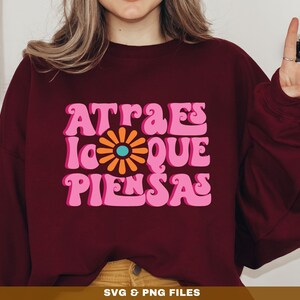 May include: A maroon sweatshirt with a pink and orange graphic design that says "Atraes lo que piensas".