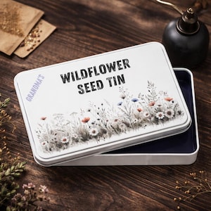 May include: A set of three ceramic mugs with a speckled, cream-coloured glaze. Each mug features a different hand-painted design: a blue and green leaf, a yellow flower, and a red berry. The mugs have a simple, rounded shape.