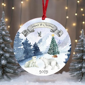 Peut inclure: Ornement de Noël rond avec une scène hivernale de ours polaires, un sapin de Noël, le texte "Ashton's 1st Christmas" et l'année 2025. L'ornement a un ruban rouge pour l'accrocher.