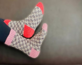 May include: A pair of knitted socks with a checkered pattern in shades of gray, pink, and red.