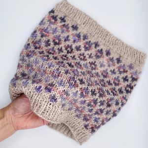 May include: A beige knitted headband with a purple and pink geometric pattern.