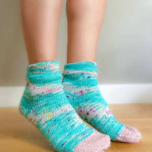 May include: A pair of teal blue ankle socks with a white and pink speckled pattern. The socks have a pink toe and heel.