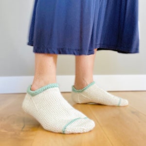May include: A pair of white ankle socks with a green trim. The socks are made of a soft, comfortable material and are perfect for everyday wear.