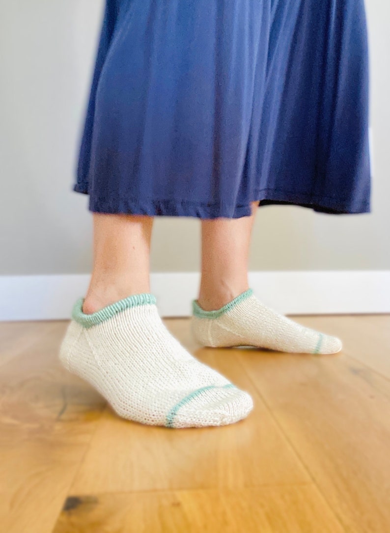 May include: A pair of white ankle socks with a green trim. The socks are made of a soft, comfortable material and are perfect for everyday wear.