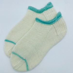 May include: A pair of white ankle socks with a teal blue trim around the top and heel.