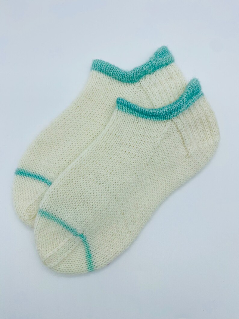 May include: A pair of white ankle socks with a teal blue trim around the top and heel.