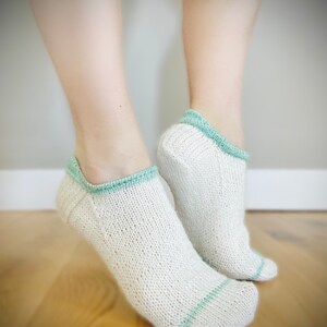 May include: A pair of white ankle socks with a light green trim. The socks are made of a soft, breathable material and are perfect for everyday wear.