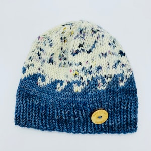 Może przedstawiać: Niebiesko-biała wełniana czapka z białym guzikiem, na którym napisano "Made for you" brązowymi literami.