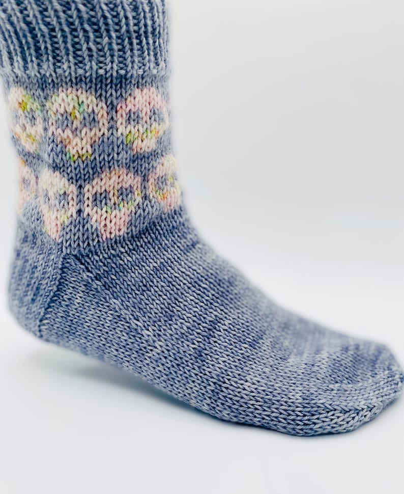 May include: A pair of blue knitted socks with a white and pink floral pattern on the cuff.