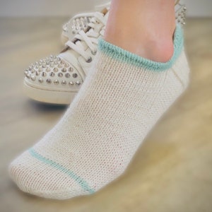 May include: White ankle socks with a light blue trim. The socks are made of a soft, knitted fabric.