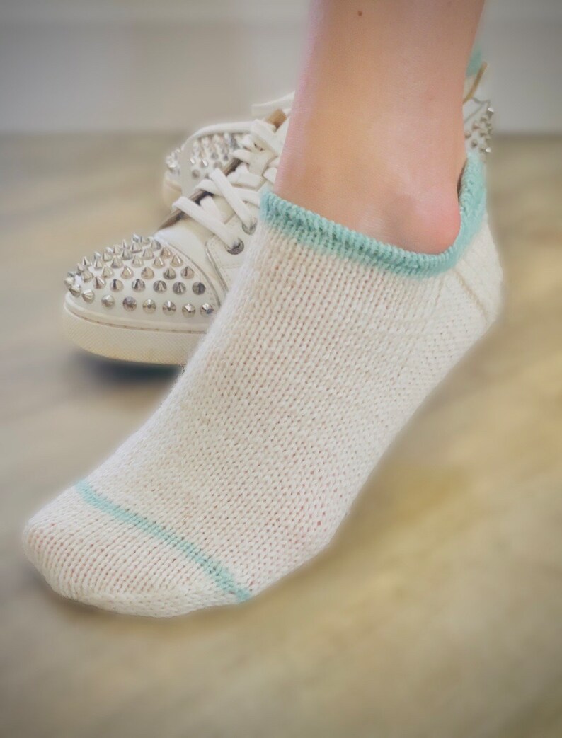 May include: White ankle socks with a light blue trim. The socks are made of a soft, knitted fabric.