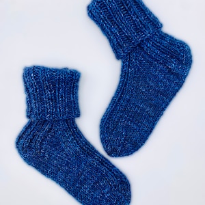 May include: Two pairs of blue knitted socks with a folded cuff. The socks are made of a soft, textured yarn.