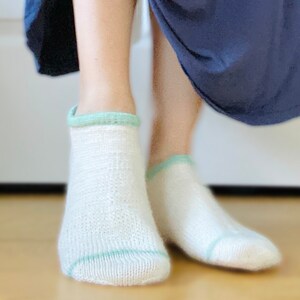 May include: A pair of white ankle socks with a light green trim around the top.