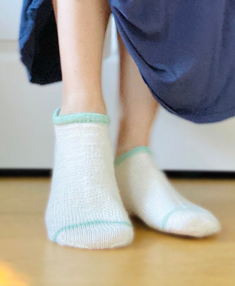 May include: A pair of white ankle socks with a light green trim around the top.