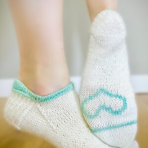 May include: A pair of white knitted socks with a light blue trim. One sock has a light blue infinity symbol design.