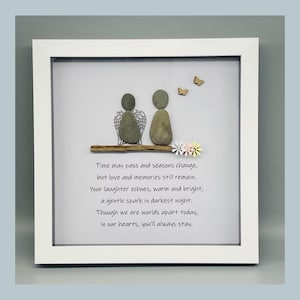 May include: Framed pebble art featuring two figures on a branch, one with wings. The white frame contains text about love and memories. Decorative butterflies and flowers are also included in the artwork. A unique gift.