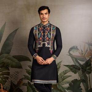 May include: Black kurta and pants set with colorful embroidered details. The kurta features a mandarin collar and intricate floral and peacock designs on the front. The cuffs and hemline are also adorned with embroidered patterns. The outfit is completed with black pants.