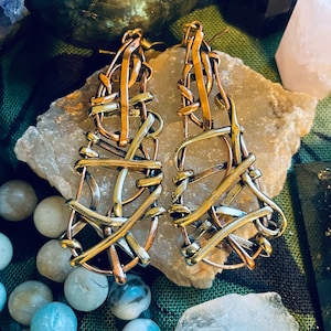 May include: A pair of earrings made from woven copper and silver wire. The earrings are a geometric design with a criss-cross pattern.
