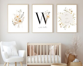May include: Three framed art prints with botanical illustrations. One features a floral bouquet, another a large letter "W" with flowers, and the third a floral wreath with the words "You are loved." The frames are light wood.