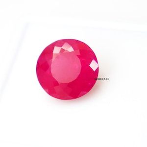 Op de afbeelding: Een ronde, gefacetteerde, roze edelsteen met een hoge glans. De edelsteen is geplaatst tegen een witte achtergrond.