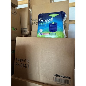 Op de afbeelding: Een stapel kartonnen dozen, sommige met de tekst "4 bags of 15" en "PF-014/1". Bovenop ligt een verpakking "Prevail PER-FIT Daily Briefs" met een blauw-groen ontwerp en de maat "XL".