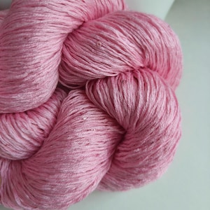 Peut inclure: Gros plan sur une pelote de fil rose. Le fil est étroitement enroulé, montrant la texture des fibres. La couleur est un rose pastel doux, idéal pour les projets de tricot ou de crochet. Le fil semble être fait d'une fibre naturelle et douce.