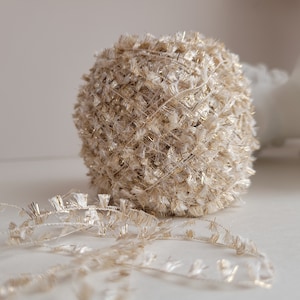 May include: A ball of white and gold yarn with a fluffy texture. The yarn is made of a thin thread with gold accents.