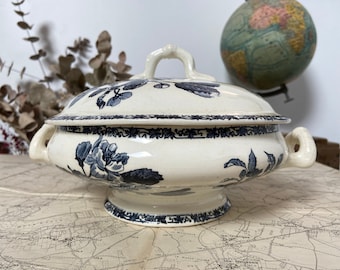 Op de afbeelding: Een witte porseleinen serveerschaal met een blauw-wit bloemenmotief. De schaal heeft een deksel en twee handvatten.