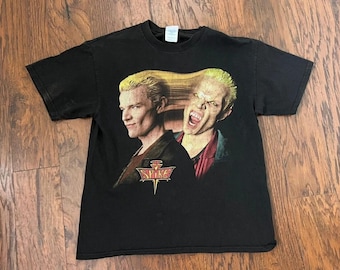 May include: A black short-sleeve t-shirt featuring a graphic print of the character Spike from Buffy the Vampire Slayer. The design shows the character in both human and vampire forms with the text SPIKE printed in a stylized yellow font below.