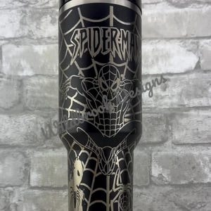 Puede incluir: Vaso aislado negro y plateado con un dise&ntilde;o de Spider-Man. El vaso tiene un cuerpo negro con un gr&aacute;fico plateado de Spider-Man, telara&ntilde;as y la palabra "SPIDER-MAN". Incluye una tapa y una pajita negras.