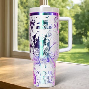 Puede incluir: Vaso t&eacute;rmico blanco con asa, con un dise&ntilde;o de "Pesadilla antes de Navidad". El dise&ntilde;o incluye a Jack Skellington, Sally y otros personajes en morado y negro. El vaso tiene una tapa blanca y un borde morado y plateado.