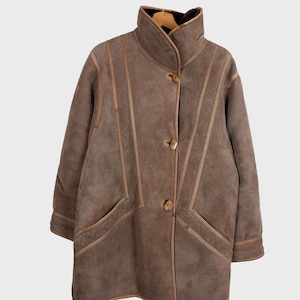 Get cozy in style with this vintage 80s shearling coat in brown. Its timeless design and soft warmth will have you feeling snug and stylish all season long. Don't miss out on this irresistible call to coziness!