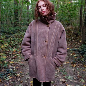 Get cozy in style with this vintage 80s shearling coat in brown. Its timeless design and soft warmth will have you feeling snug and stylish all season long. Don't miss out on this irresistible call to coziness!