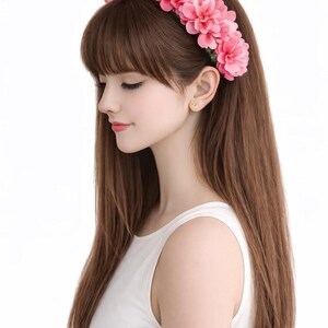 Op de afbeelding: Een vrouw met lang bruin haar draagt een roze bloemenkrans en een witte tanktop. De bloemenkrans is gemaakt van meerdere roze bloemen. De vrouw kijkt naar beneden met haar ogen gesloten.