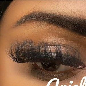 May include: Close-up of a person's eye with long, dark eyelashes. The eye is closed and the eyelashes are fanned out. The person's eyebrow is also visible and is dark and well-defined.