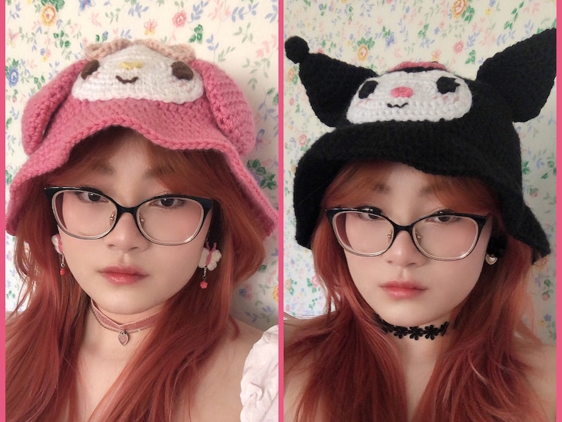 May include: Two women with red hair are wearing crocheted hats. The hat on the left is pink with a white character on the front. The hat on the right is black with a white character on the front. Both women are wearing glasses.
