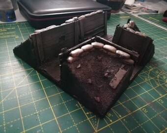 May include: A detailed model of a trench with sandbags, wooden planks, and a dirt floor. The model is painted in shades of brown, black, and gray.