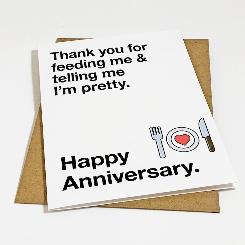 Puede incluir: Tarjeta blanca con texto negro que dice "Gracias por alimentarme y decirme que soy bonita. Feliz aniversario." Una ilustraci&oacute;n en blanco y negro de un tenedor, un plato con un coraz&oacute;n rojo y un cuchillo est&aacute; debajo del texto.